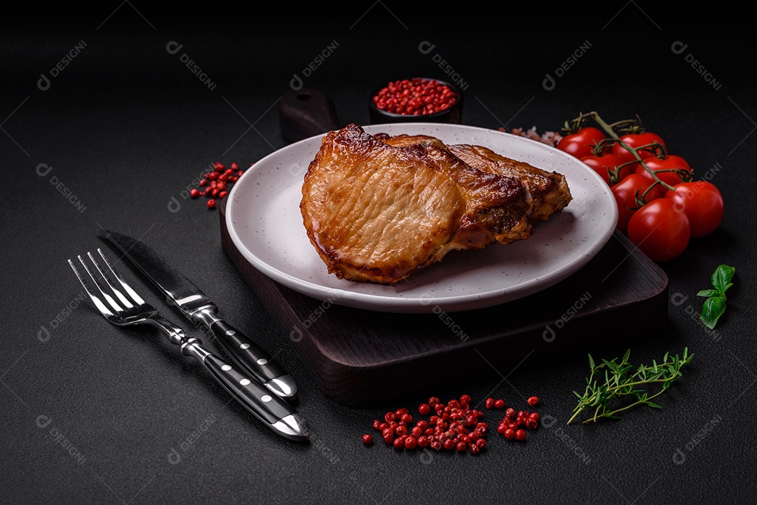 Delicioso suculento bife de porco ou de vaca com sal, especiarias e ervas sobre um fundo de concreto texturizado