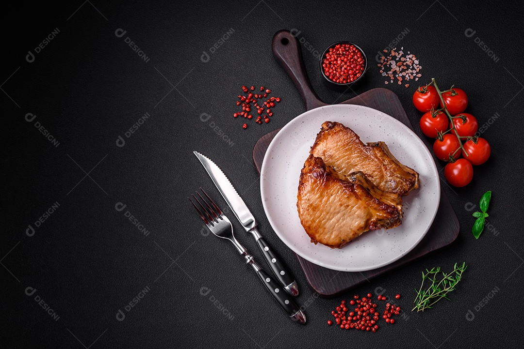 Delicioso suculento bife de porco ou de vaca com sal, especiarias e ervas sobre um fundo de concreto texturizado