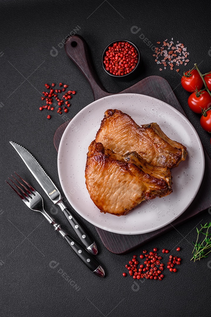 Delicioso suculento bife de porco ou de vaca com sal, especiarias e ervas sobre um fundo de concreto texturizado