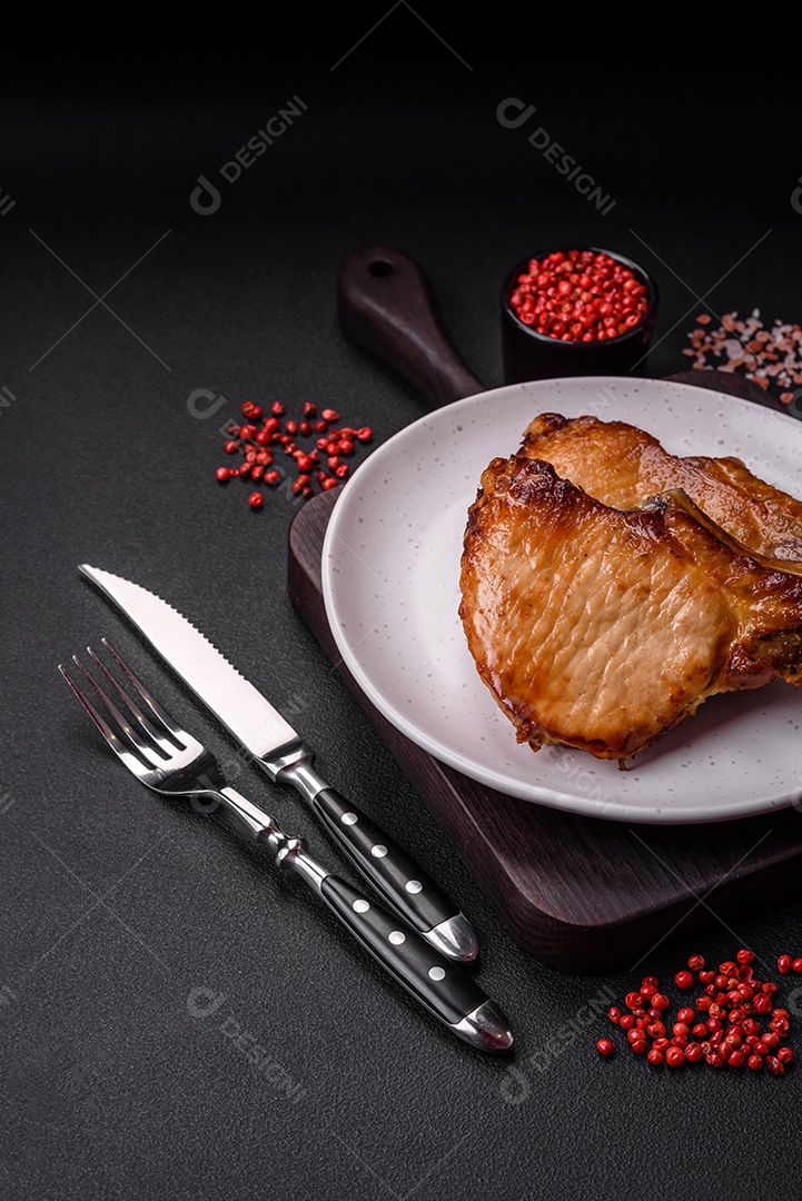 Delicioso suculento bife de porco ou de vaca com sal, especiarias e ervas sobre um fundo de concreto texturizado