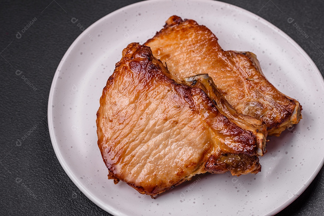 Delicioso suculento bife de porco ou de vaca com sal, especiarias e ervas sobre um fundo de concreto texturizado