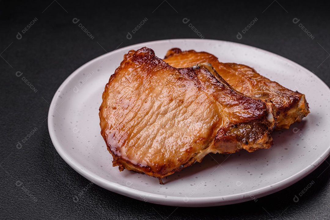 Delicioso suculento bife de porco ou de vaca com sal, especiarias e ervas sobre um fundo de concreto texturizado