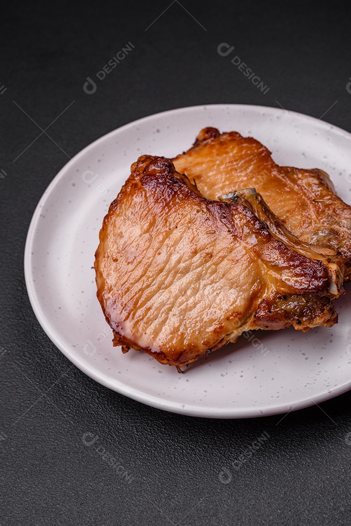 Delicioso suculento bife de porco ou de vaca com sal, especiarias e ervas sobre um fundo de concreto texturizado