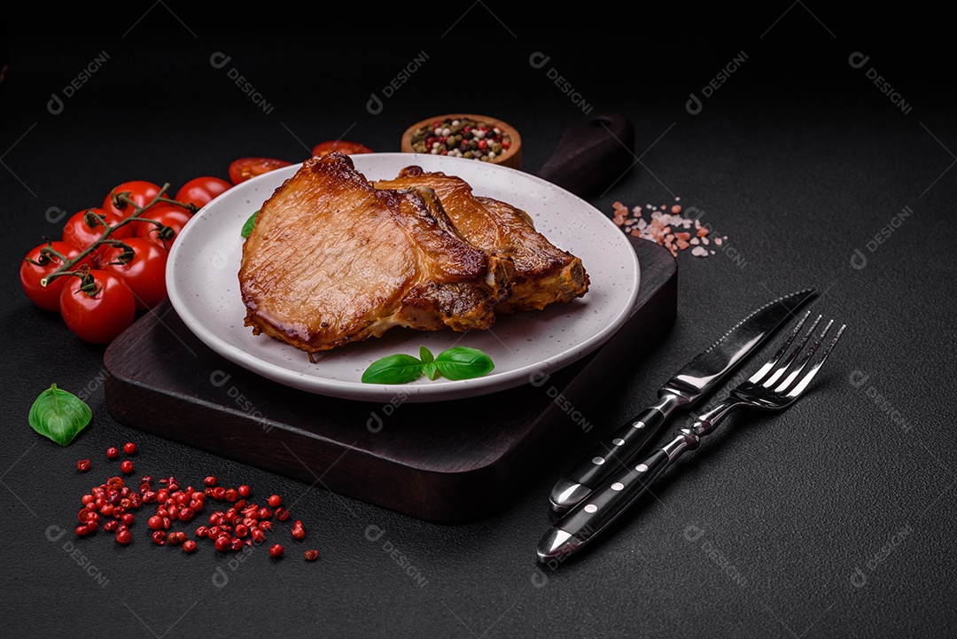 Delicioso suculento bife de porco ou de vaca com sal, especiarias e ervas sobre um fundo de concreto texturizado