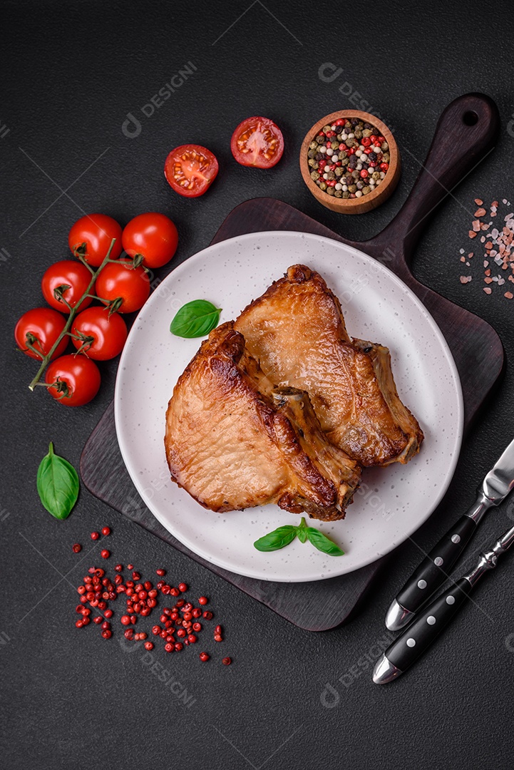 Delicioso suculento bife de porco ou de vaca com sal, especiarias e ervas sobre um fundo de concreto texturizado