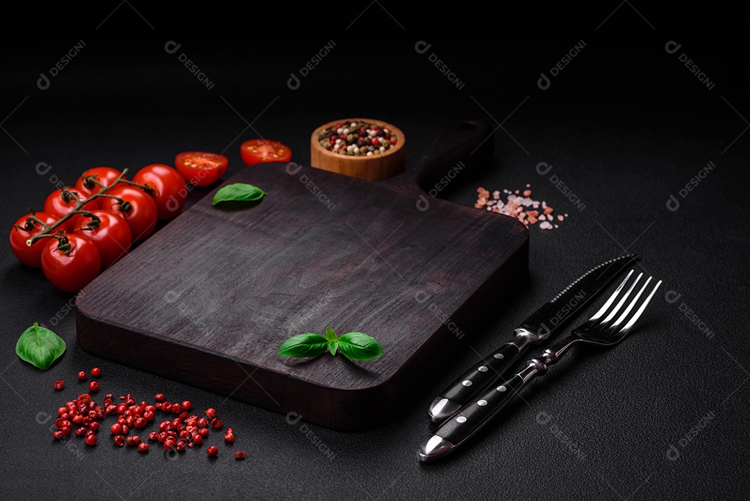 Ingredientes para cozinhar tomate cereja, sal, especiarias e ervas sobre um fundo escuro de concreto