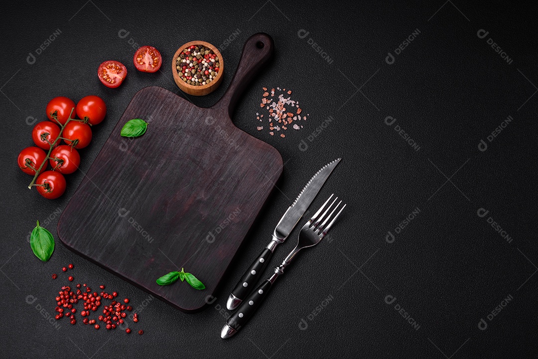 Ingredientes para cozinhar tomate cereja, sal, especiarias e ervas sobre um fundo escuro de concreto