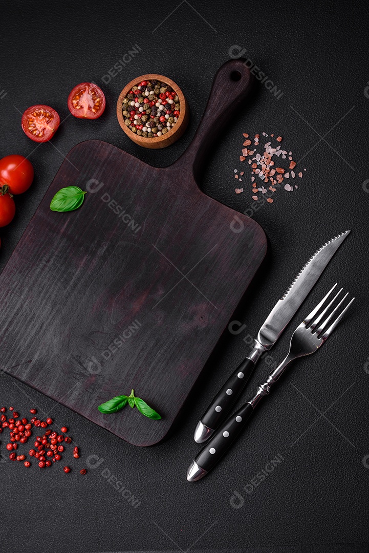 Ingredientes para cozinhar tomate cereja, sal, especiarias e ervas sobre um fundo escuro de concreto