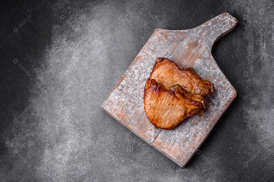 Delicioso suculento bife de porco ou de vaca com sal, especiarias e ervas sobre um fundo de concreto texturizado