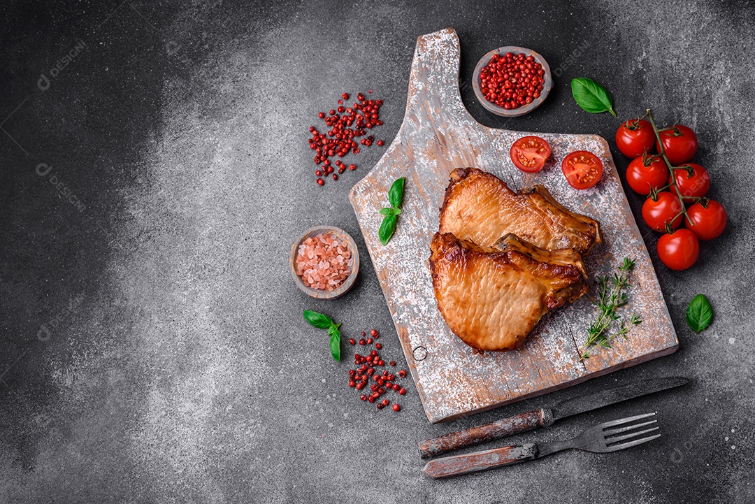 Delicioso suculento bife de porco ou de vaca com sal, especiarias e ervas sobre um fundo de concreto texturizado