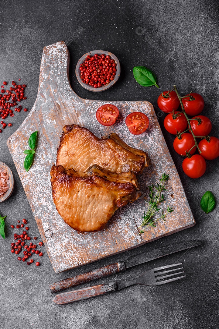 Delicioso suculento bife de porco ou de vaca com sal, especiarias e ervas sobre um fundo de concreto texturizado