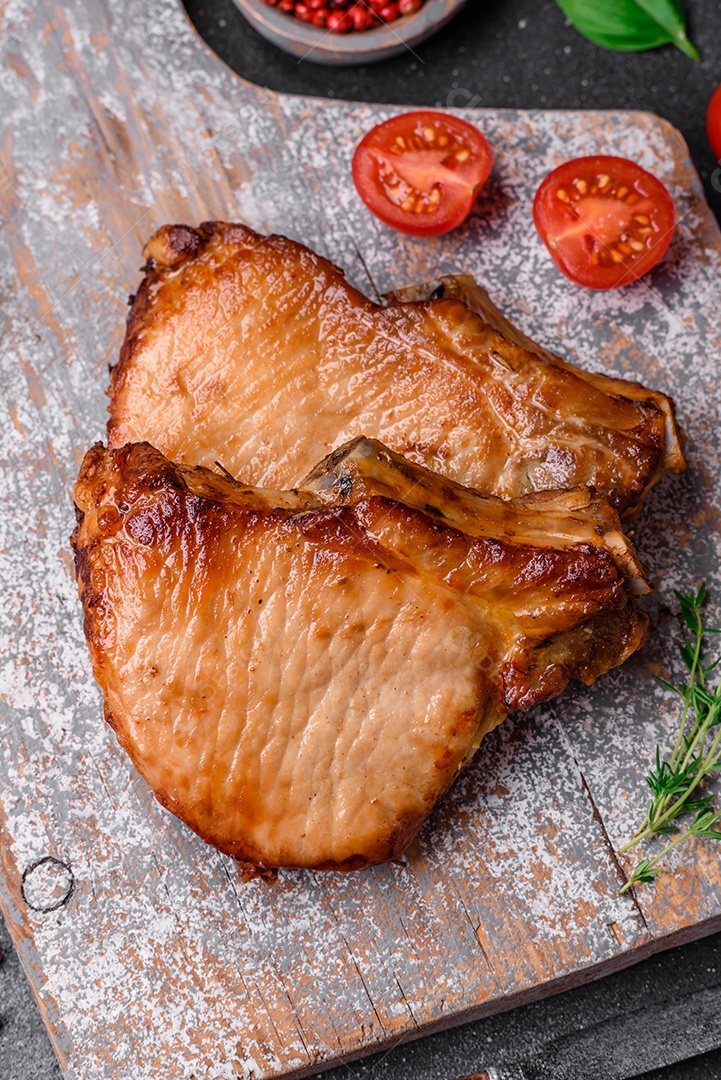 Delicioso suculento bife de porco ou de vaca com sal, especiarias e ervas sobre um fundo de concreto texturizado