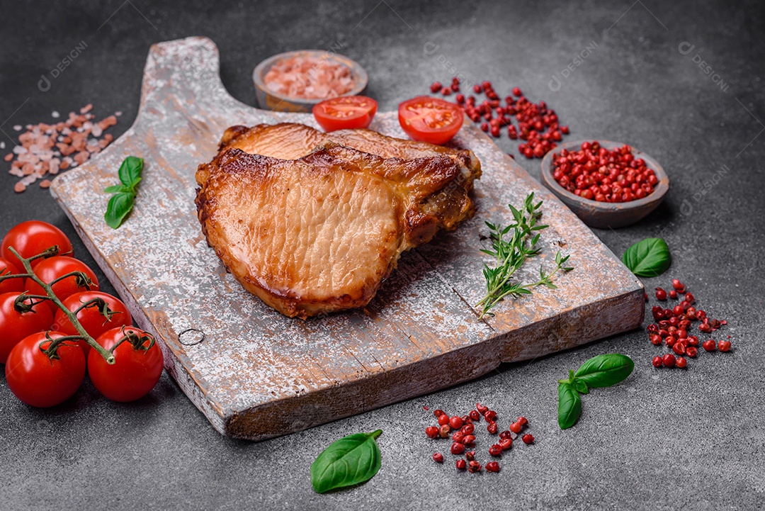 Delicioso suculento bife de porco ou de vaca com sal, especiarias e ervas sobre um fundo de concreto texturizado