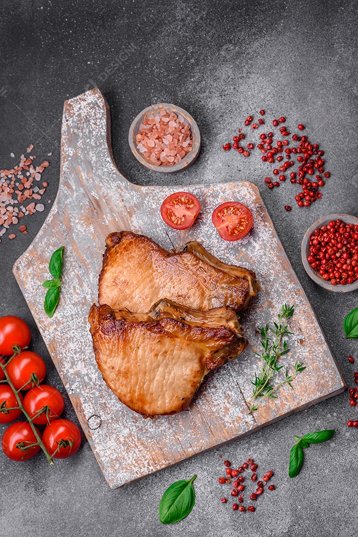 Delicioso suculento bife de porco ou de vaca com sal, especiarias e ervas sobre um fundo de concreto texturizado