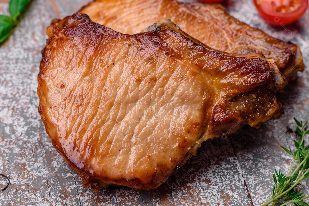 Delicioso suculento bife de porco ou de vaca com sal, especiarias e ervas sobre um fundo de concreto texturizado