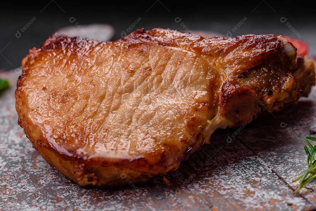 Delicioso suculento bife de porco ou de vaca com sal, especiarias e ervas sobre um fundo de concreto texturizado