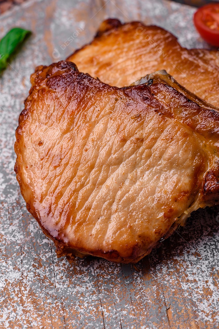 Delicioso suculento bife de porco ou de vaca com sal, especiarias e ervas sobre um fundo de concreto texturizado