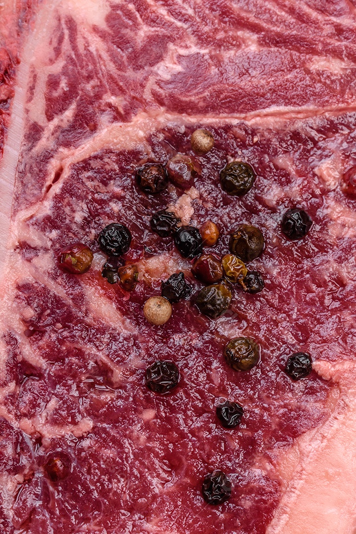 Bife fresco e suculento de Nova Iorque com sal, especiarias e ervas em fundo escuro de concreto