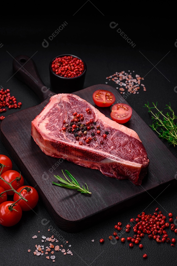 Bife fresco e suculento de Nova Iorque com sal, especiarias e ervas em fundo escuro de concreto