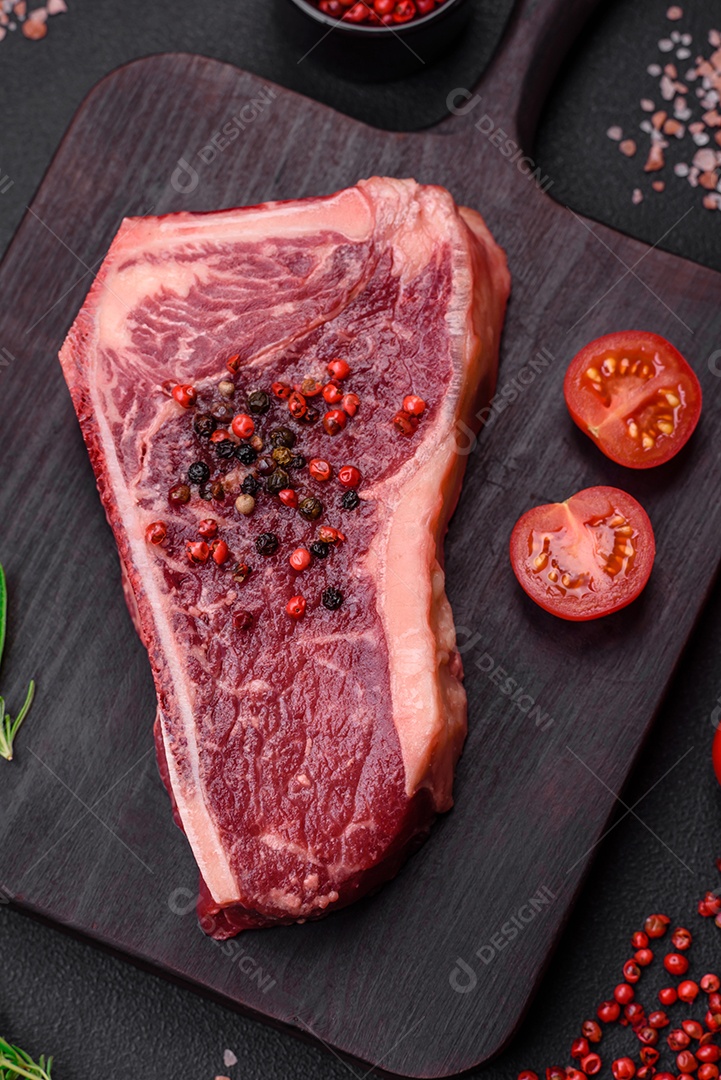 Bife fresco e suculento de Nova Iorque com sal, especiarias e ervas em fundo escuro de concreto