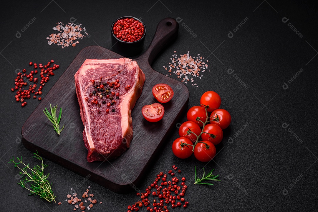 Bife fresco e suculento de Nova Iorque com sal, especiarias e ervas em fundo escuro de concreto