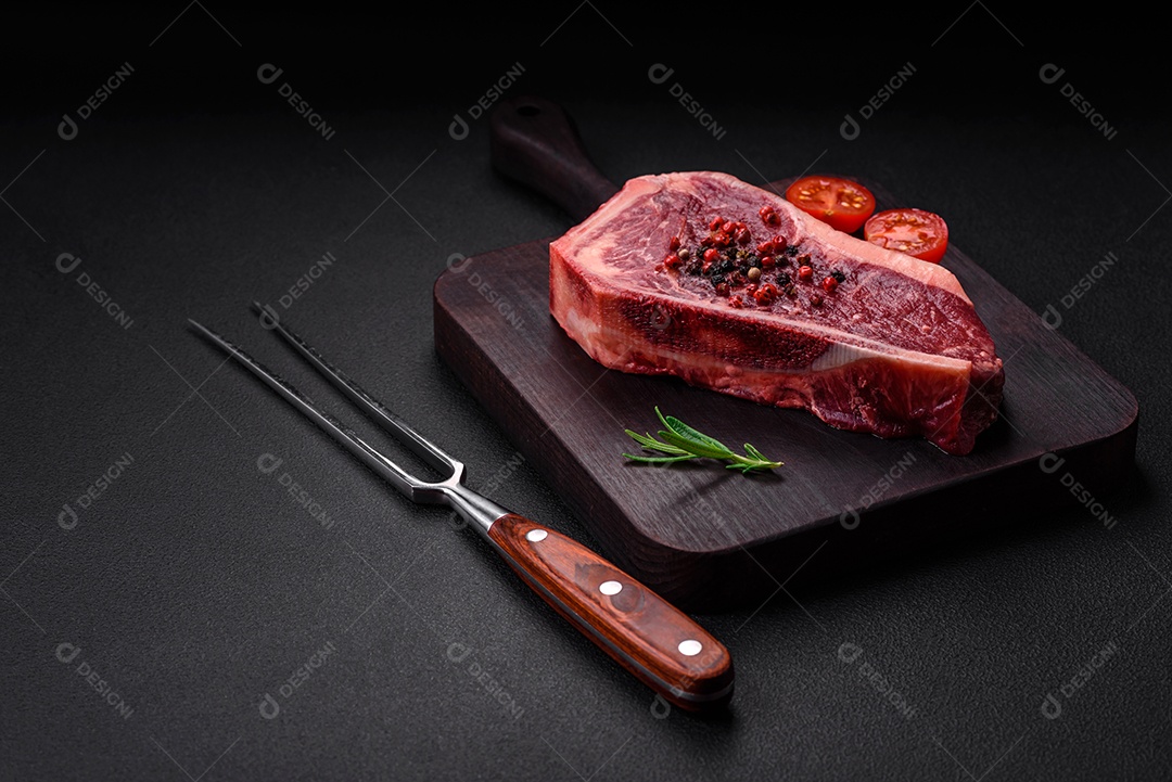 Bife fresco e suculento de Nova Iorque com sal, especiarias e ervas em fundo escuro de concreto