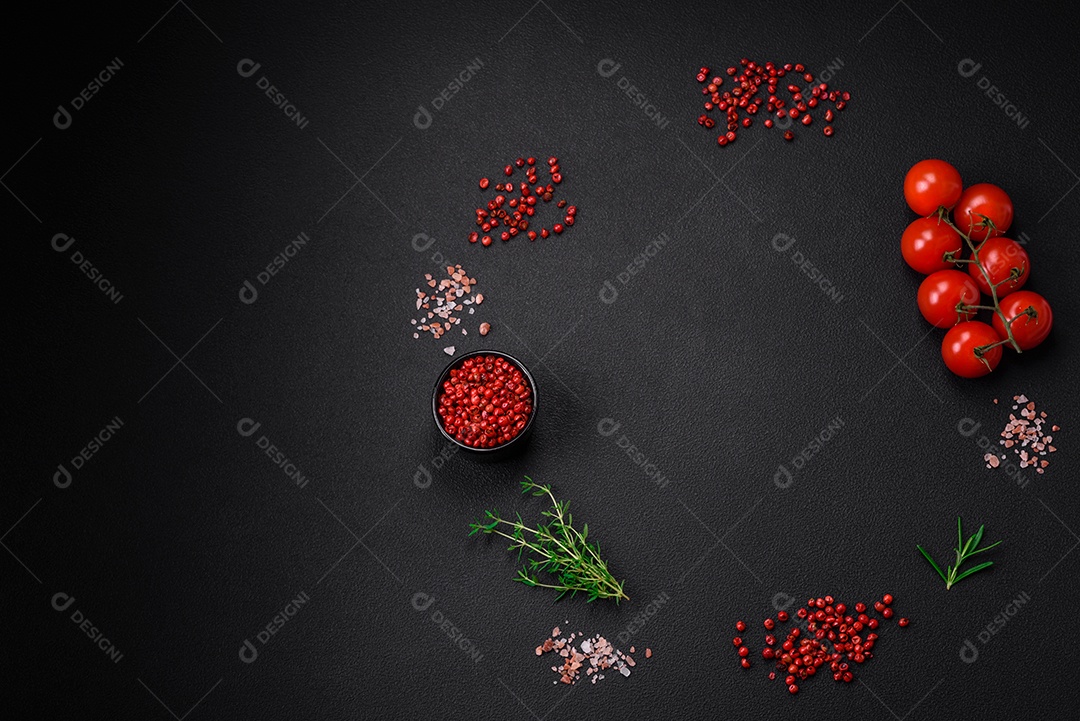 Ingredientes para cozinhar tomate cereja, sal, especiarias e ervas sobre um fundo escuro de concreto