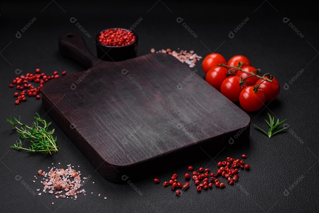 Ingredientes para cozinhar tomate cereja, sal, especiarias e ervas sobre um fundo escuro de concreto