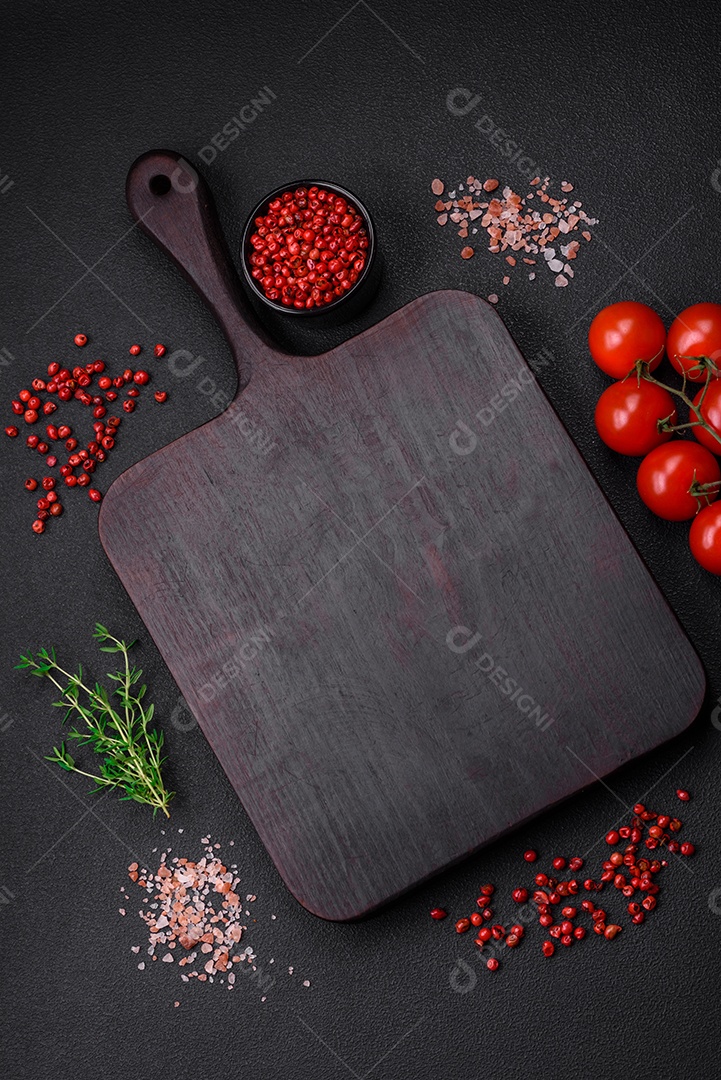 Ingredientes para cozinhar tomate cereja, sal, especiarias e ervas sobre um fundo escuro de concreto