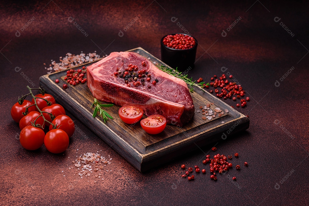 Bife fresco e suculento de Nova Iorque com sal, especiarias e ervas em fundo escuro de concreto