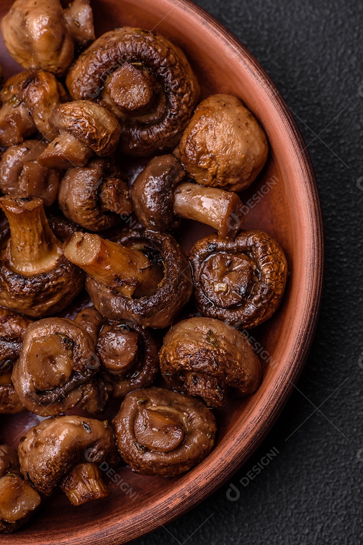 Deliciosos cogumelos champignon com sal, especiarias e ervas grelhados num prato de cerâmica