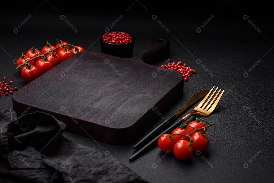 Ingredientes para cozinhar tomate cereja, sal, especiarias e ervas sobre um fundo escuro de concreto