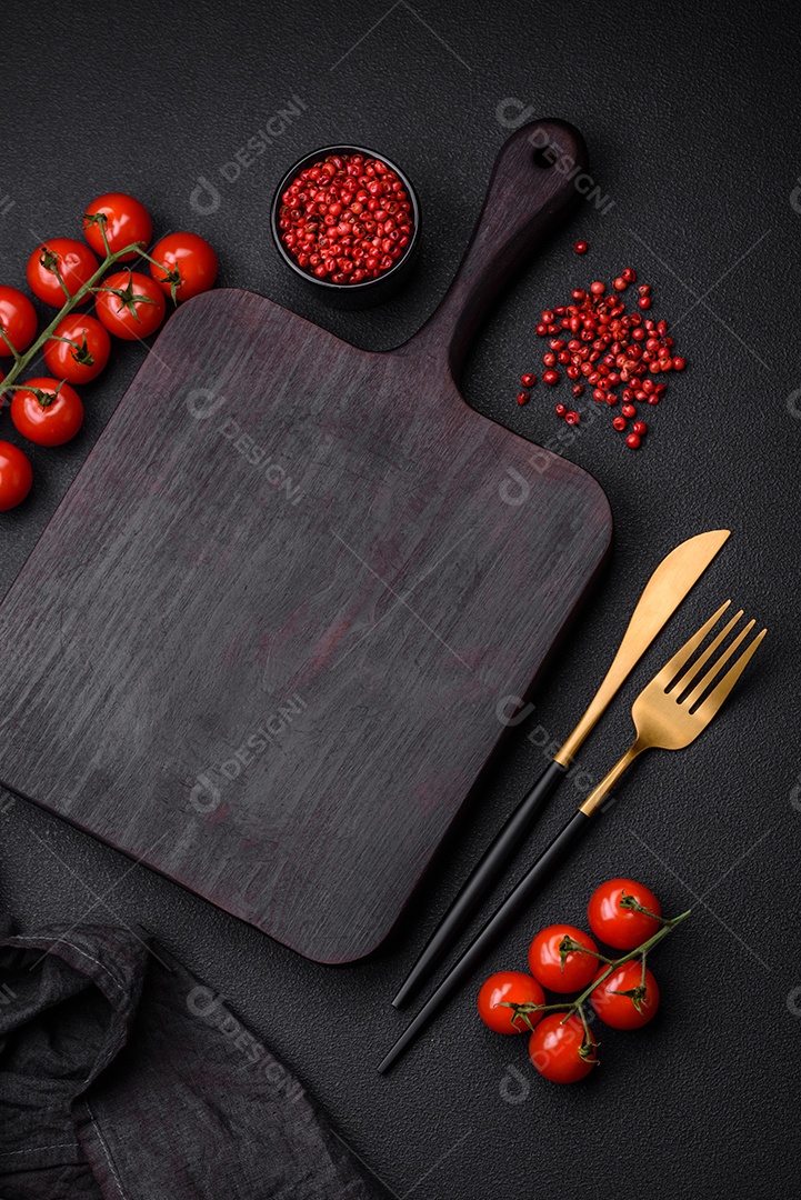 Ingredientes para cozinhar tomate cereja, sal, especiarias e ervas sobre um fundo escuro de concreto