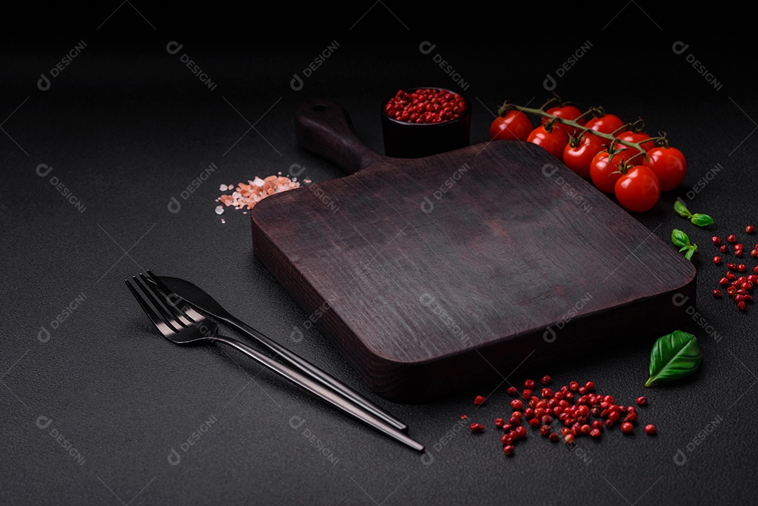 Ingredientes para cozinhar tomate cereja, sal, especiarias e ervas sobre um fundo escuro de concreto