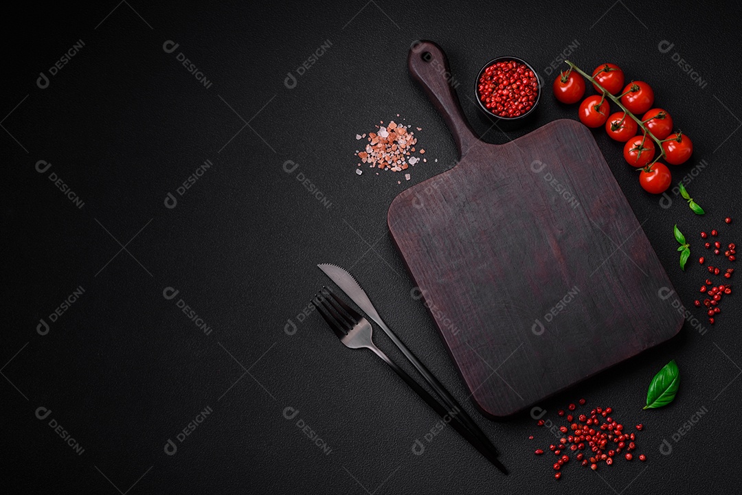 Ingredientes para cozinhar tomate cereja, sal, especiarias e ervas sobre um fundo escuro de concreto