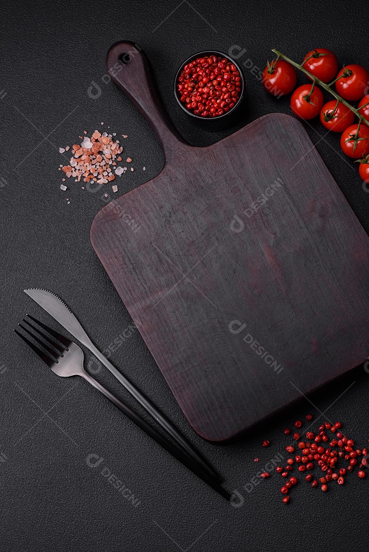 Ingredientes para cozinhar tomate cereja, sal, especiarias e ervas sobre um fundo escuro de concreto