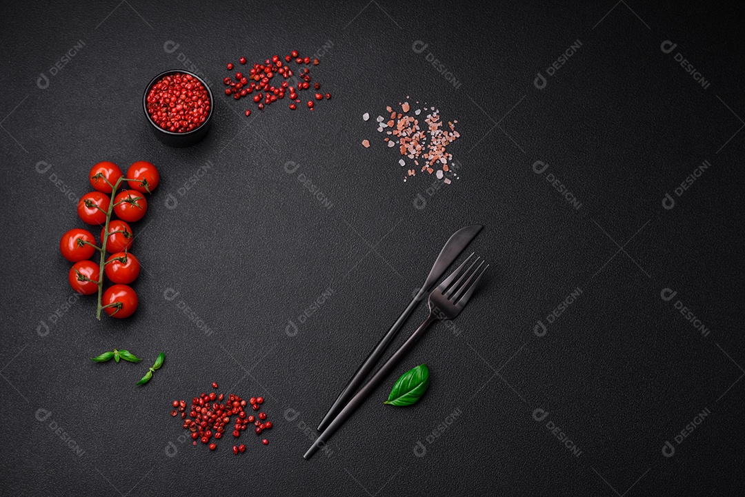 Ingredientes para cozinhar tomate cereja, sal, especiarias e ervas sobre um fundo escuro de concreto
