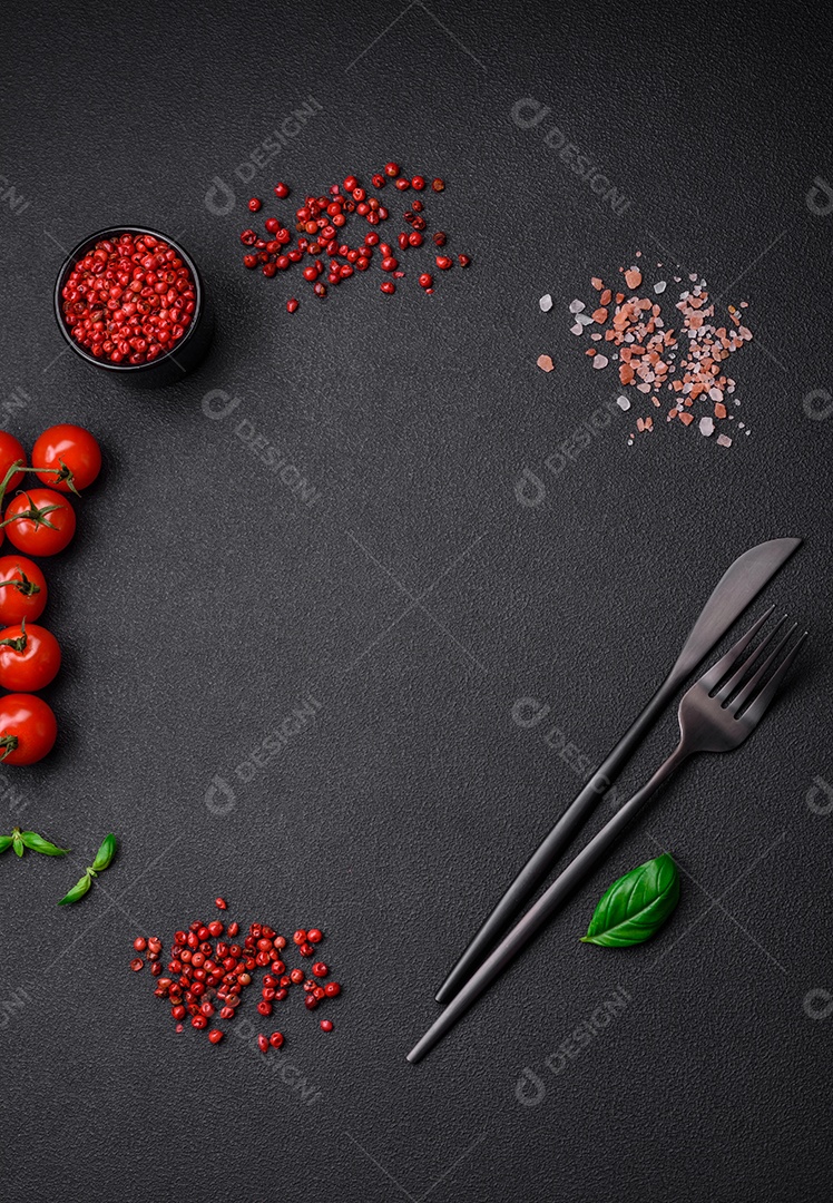 Ingredientes para cozinhar tomate cereja, sal, especiarias e ervas sobre um fundo escuro de concreto