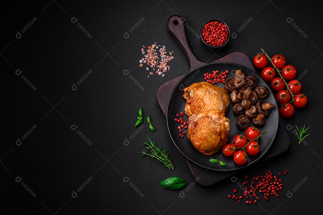 Deliciosas coxas de frango suculentas assadas com sal, especiarias e ervas em uma placa cerâmica sobre um fundo escuro de concreto