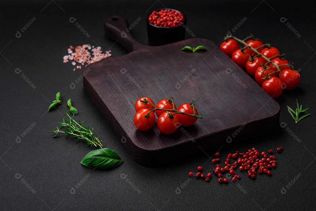 Ingredientes para cozinhar tomate cereja, sal, especiarias e ervas sobre um fundo escuro de concreto