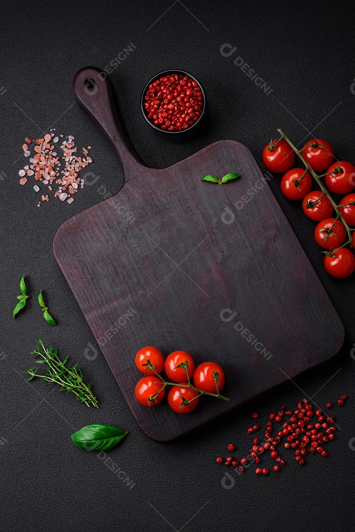 Ingredientes para cozinhar tomate cereja, sal, especiarias e ervas sobre um fundo escuro de concreto