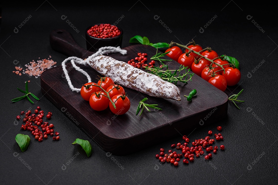 Deliciosa salsicha fuet fumada fresca com sal, especiarias e ervas sobre um fundo escuro de concreto