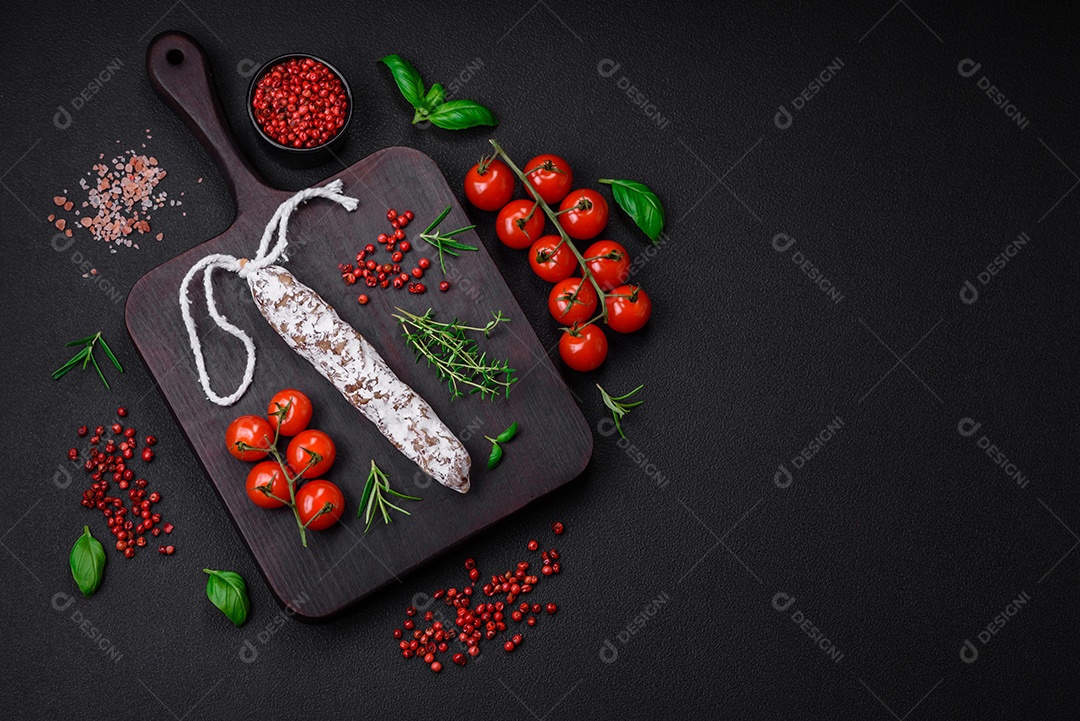 Deliciosa salsicha fuet fumada fresca com sal, especiarias e ervas sobre um fundo escuro de concreto