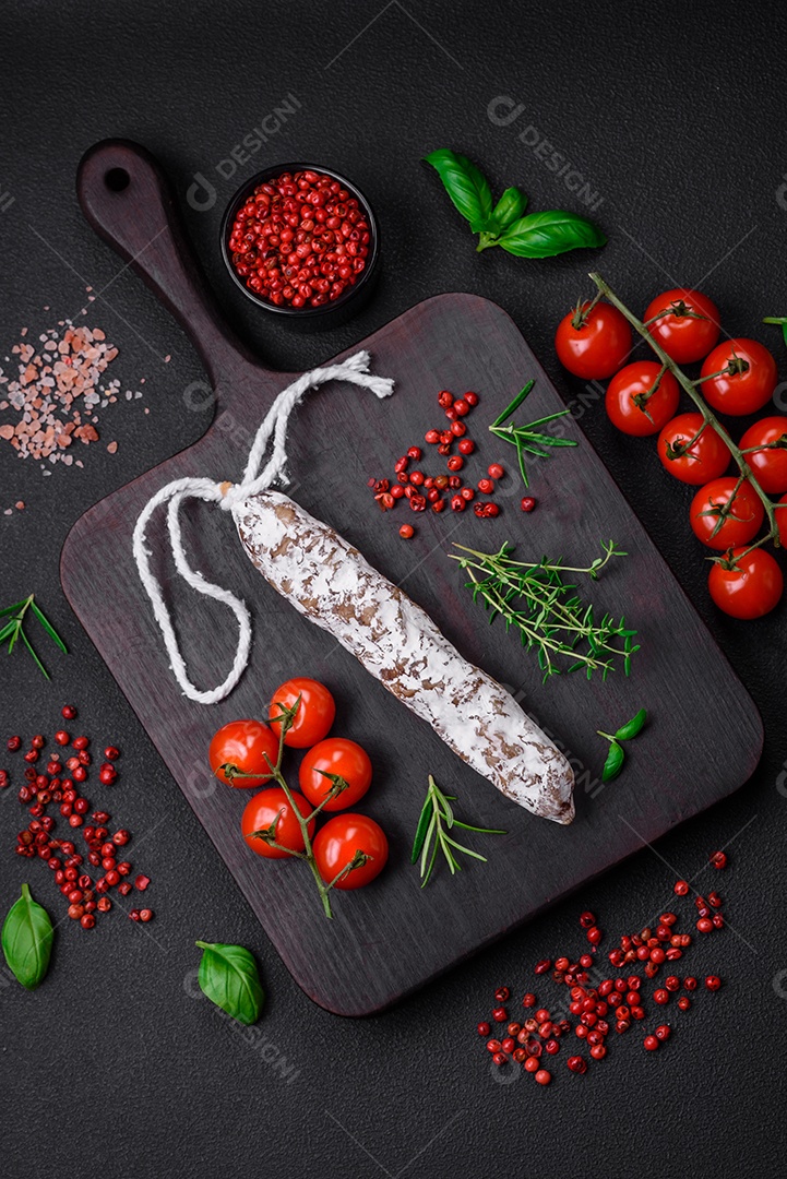 Deliciosa salsicha fuet fumada fresca com sal, especiarias e ervas sobre um fundo escuro de concreto