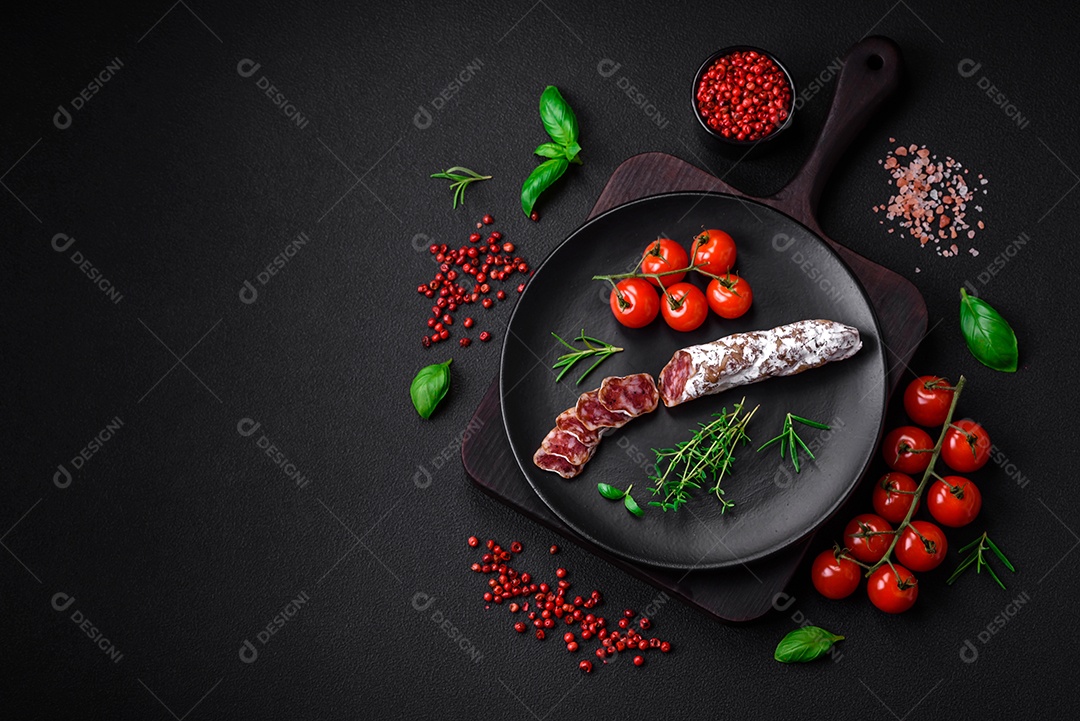 Deliciosa salsicha fuet fumada fresca com sal, especiarias e ervas sobre um fundo escuro de concreto