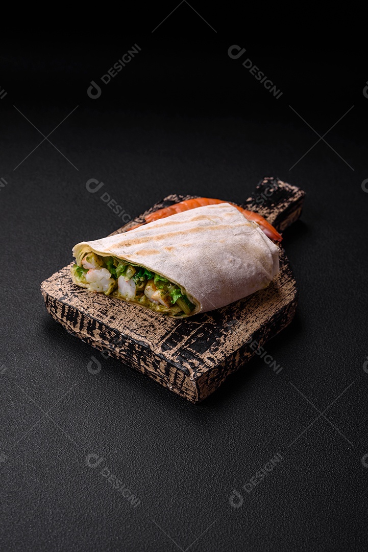 Delicioso pão fresco com camarões, tomates, alface e pepino em pão pita sobre um fundo escuro de concreto