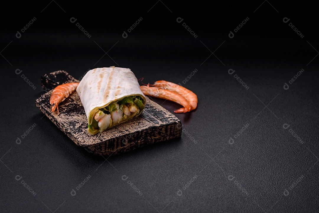 Delicioso pão fresco com camarões, tomates, alface e pepino em pão pita sobre um fundo escuro de concreto
