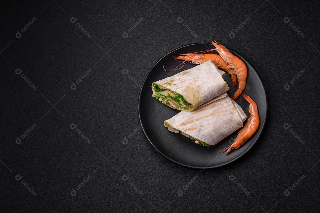 Delicioso pão fresco com camarões, tomates, alface e pepino em pão pita sobre um fundo escuro de concreto