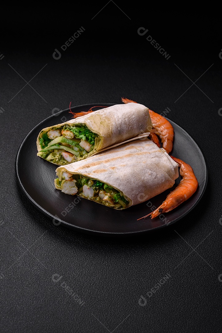 Delicioso pão fresco com camarões, tomates, alface e pepino em pão pita sobre um fundo escuro de concreto