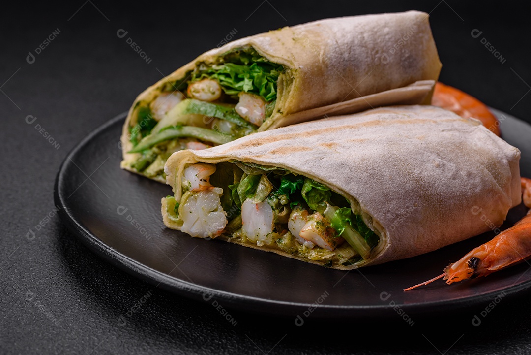 Delicioso pão fresco com camarões, tomates, alface e pepino em pão pita sobre um fundo escuro de concreto